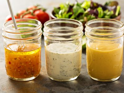 Variety of homemade sauces and salad dressings in mason jars including vinaigrette, ranch and honey mustard
